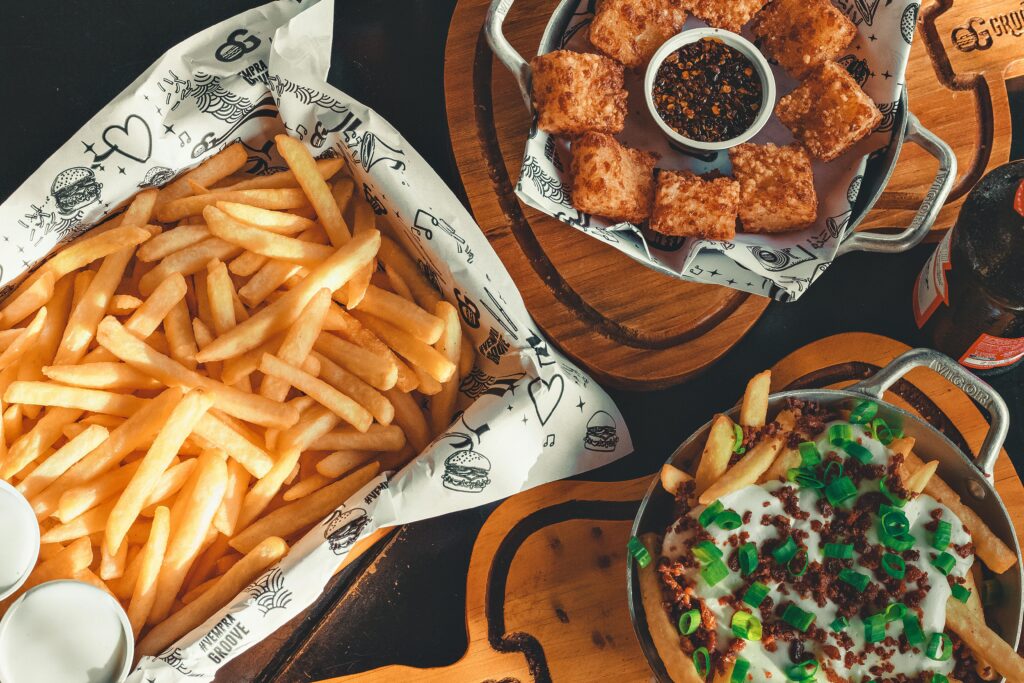 Delicious platter of crispy fries, loaded fries, cheese bites, and dips on a rustic wooden table.